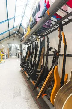 Guitars workshop, guitars with different shapes, patterns and types hanging at Stock Photos
