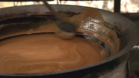 Gula Apong molasses boiling in a large wok as a scoop stirs it. Stock Footage 283097750