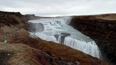 Gullfoss waterfall rushing through steep canyon under overcast sky, wide angl Stock Footage 336869686