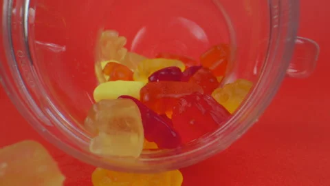 Gummy bears in jar on red background. Camera moving out of sweet candy jar Stock Footage 139307700