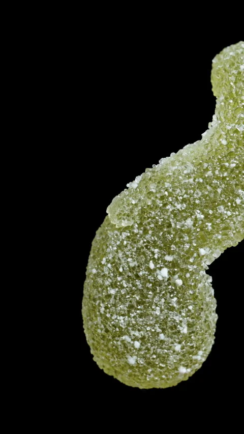 A gummy candy in the shape of a worm or larva, dusted with sugar. It rotates on Stock Footage 249609449