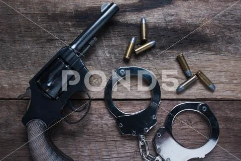 Gun with ammunition and shackle on wood background, Top view Stock Photos