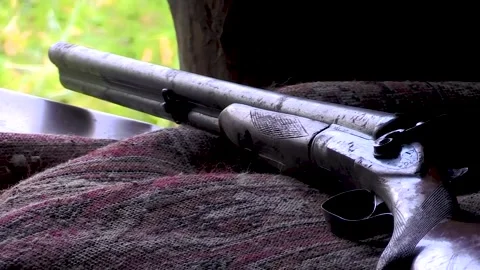 The gun is lying on the bedspread. The muzzle of a gun looks out the open window Video stock 253661240