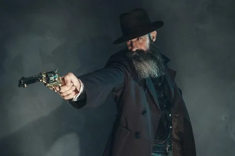 Gun shooting vintage crook with long beard in 1900 style clothing against gre Stock Photos