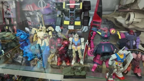 Gundam robot action figures and model kits in a glass display cabinet. Video stock 341401462