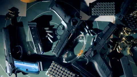 Guns, bullets, headphones and protection glasses for shooting in a top view Stock Footage