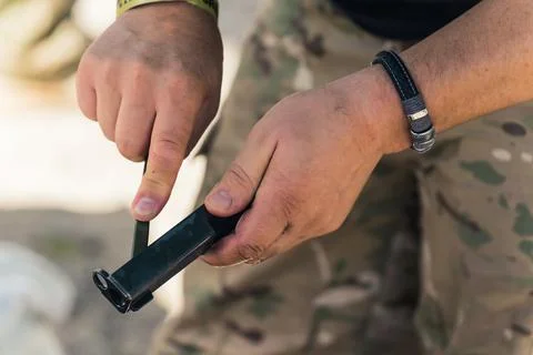 Gunsmithing concept. Two hands of an unrecognizable caucasian man in moro pants Stock Photos