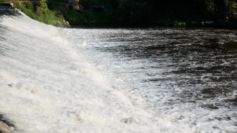 Gushing water over dam on Ave River in Portugal on a bright, sunny day Stock Footage 112765355
