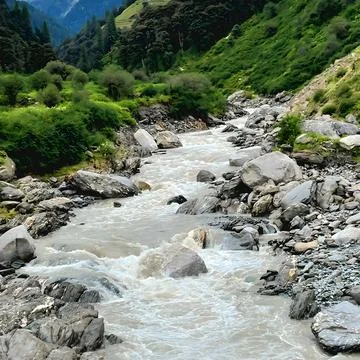 Gushing white water stream cascading through giant boulders and green mountain s Stock Photos