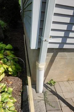 Gutter down spot emptying into a drain that goes through a patio block into.. Stock Photos