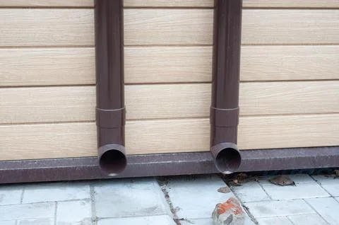 Gutter with downpipe on the roof of a house. Stock Photos