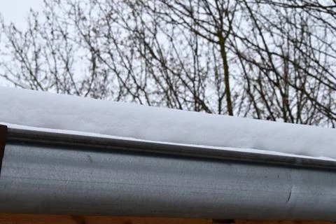 The gutter on the roof of the snow. Stock Photos