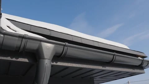 Gutter system on a house roof with snow and clear blue sky, close-up cinema.. Stock Footage 334849062