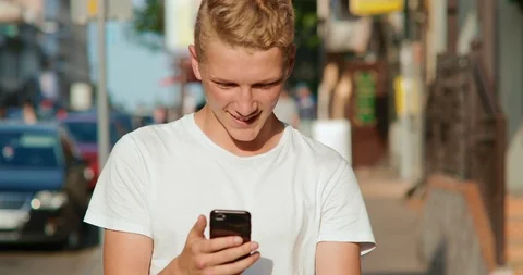 A guy 18 years old is walking around the city with a phone in his hands Stock Footage 91512224