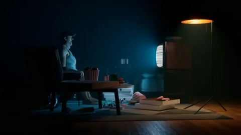 A guy from '90  in the dark room staring at tv surrounded by snacks and drinks. Stock Footage 133435691