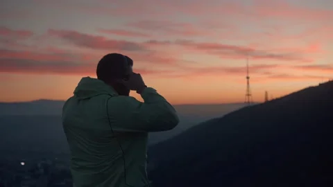 The guy after morning run standing and calm down with a great sunrise view . Video stock 239551655