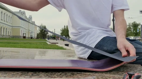 Guy aligns the rough surface and puts it on the skateboard 库存影片 80551777