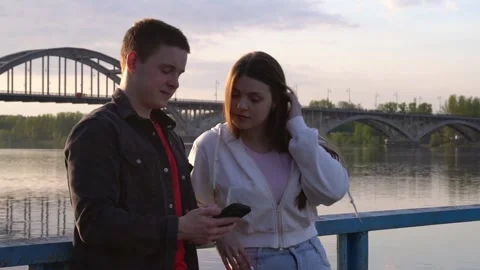 A guy and a girl are scrolling through a tape on a smartphone, looking at the Stock Footage 310487189