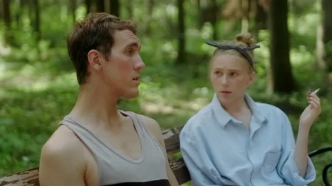 A guy and a girl communicate on a bench in the forest. Stock Footage 197481386