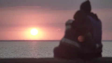 Guy and girl cuddling and watching the sunset Stock Footage