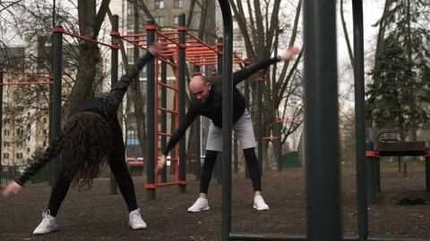 A guy and a girl do a warm-up on the sports field Stock Footage 237992199