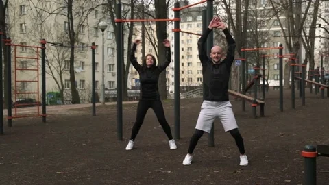 A guy and a girl do a warm-up on the sports field, a woman and a man do sports Stock Footage 237994042