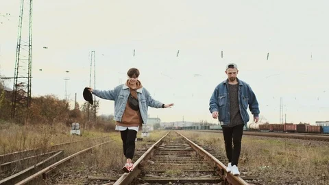 Guy And The Girl Go On The Parallel Rails Of The Railway Track. They Try To Keep Stock Footage 124595231