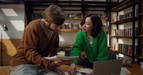 Guy and girl students communicate and discuss ideas while sitting on a table in Stock Footage 313356489