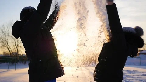 A guy and a girl throws snow above head and hugging on sunset background Видео 70989152