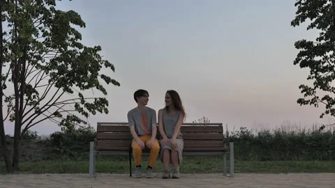 Guy and girls laugh while sitting on the bench Stock Footage 135735988