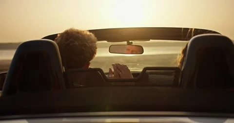 A guy and his girlfriend are talking in a convertible car. A girl and a boy sit Stock Footage 250077659