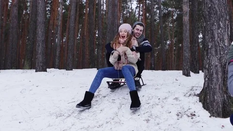 Guy and his girlfriend riding down a steep hill on a toboggan Stock Footage 70989633