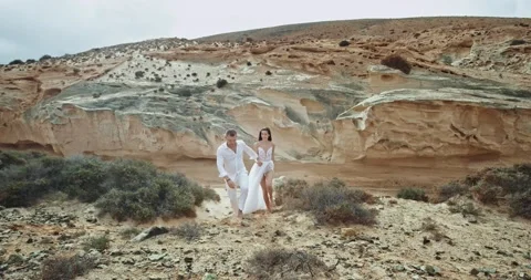 Guy and lady walking through the rocks in amazing landscape view they wearing Stock Footage 135233588