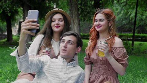 A guy and two girls are talking on the phone via video link in nature in the Stock Footage 171823686