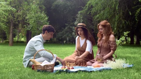 A guy and two girls had a picnic and started playing chess in nature in the Stock Footage 158388404