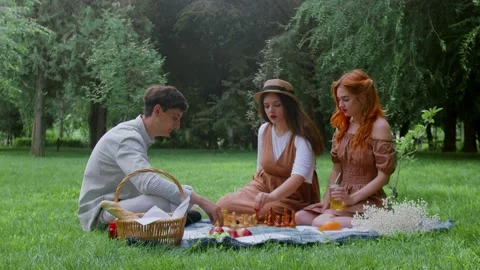 A guy and two girls had a picnic and started playing chess in nature in the Stock Footage 171834424