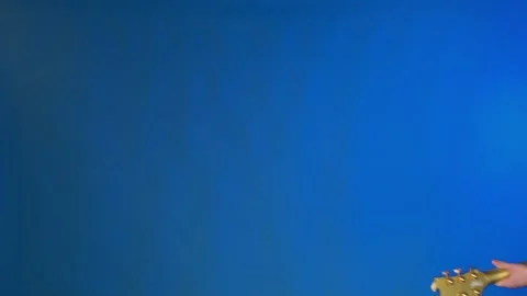 Guy appears and leaves frame playing guitar, on blue background Stock Footage 132814651