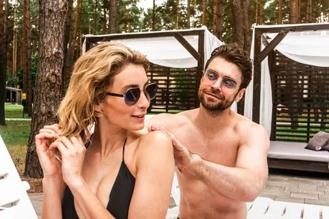 Guy applying a coat of sunscreen to the back skin of his female companion before Stock Photos