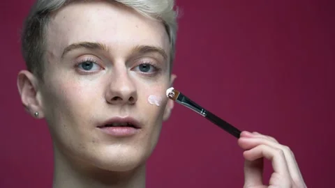 Guy applying makeup with brush on his face. Beauty, skin care concept 库存影片 153630889