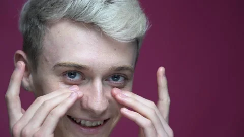 Guy applying moisturizer on face isolated on red background Stock-Footage 154931126