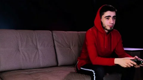 Guy are sitting on the couch in front of the TV and excited playing a game Stock Footage 134205154