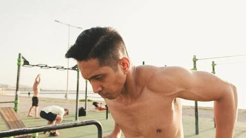 Guy, the athlete does push-ups on the parallel bars on the outdoor sports g.. Stock Photos