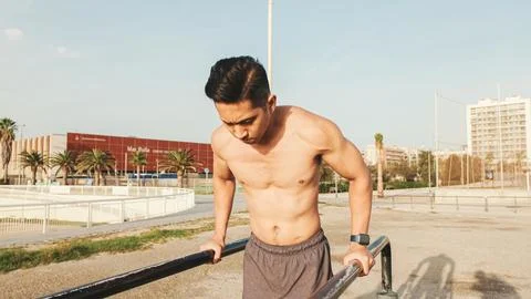 Guy, the athlete does push-ups on the parallel bars on the outdoor sports g.. Stock Photos