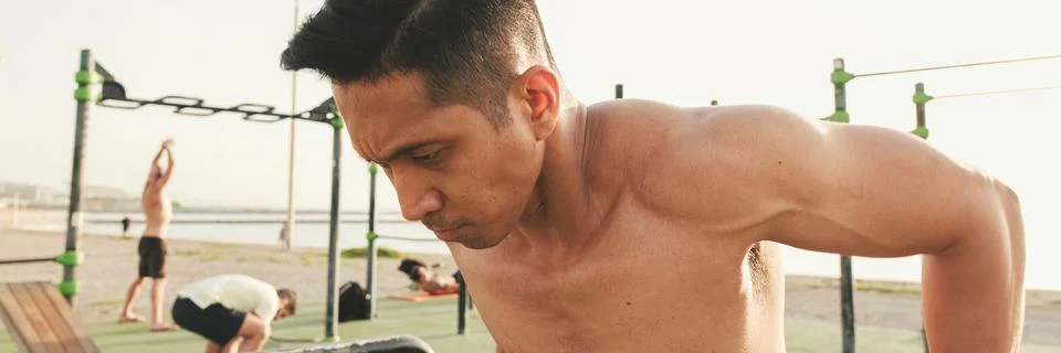 Guy, the athlete does push-ups on the parallel bars on the outdoor sports g.. Stock Photos