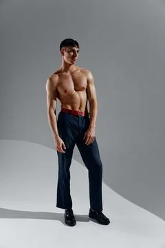 Guy athlete with a pumped-up torso bodybuilder Fitness gray background jeans Stock Photos