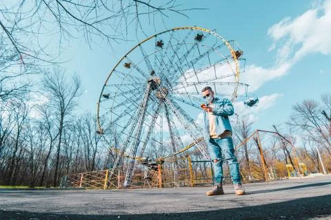 Guy on the background of an empty ferris wheel in the park alone 写真素材