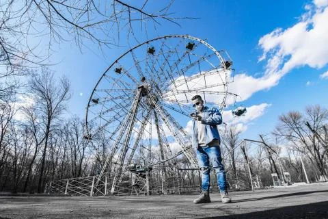 Guy on the background of an empty ferris wheel in the park alone Stock Photos