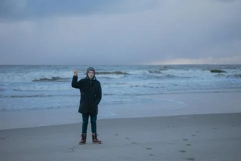 The guy on the background of the sea shows two fingers with a gesture (peace) Stock Photos