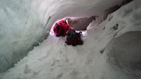 Guy with a backpack climbing into an ice cave 스톡 동영상 234510217