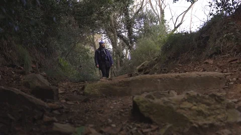 A guy with a backpack goes down a steep slope in the forest Barcelona Stock Footage 101270347